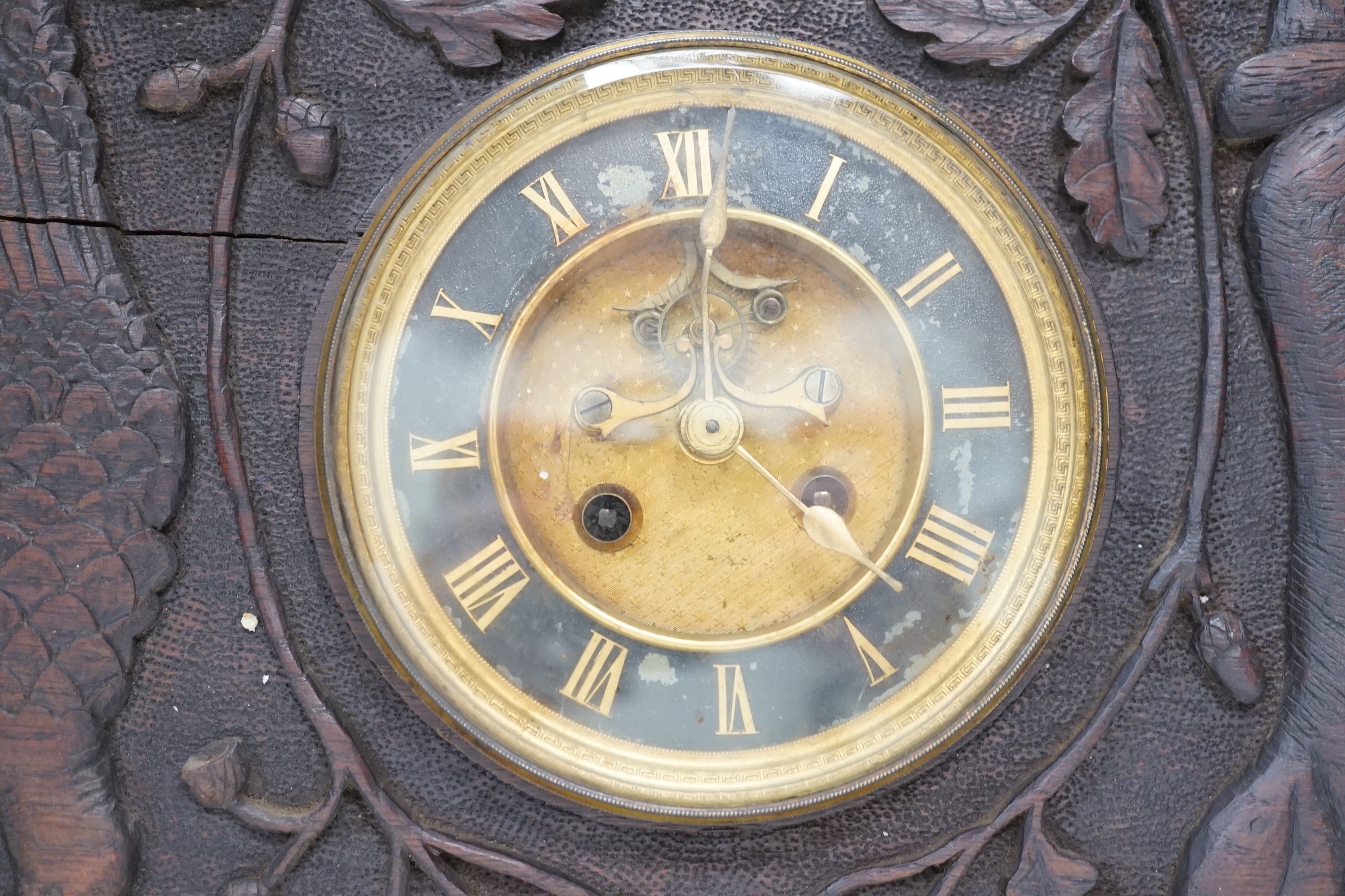 A late 19th century / early 20th century folk art carved oak cased clock, decorated with hanging dead game amongst oak sprigs and acorns, 34x39cm